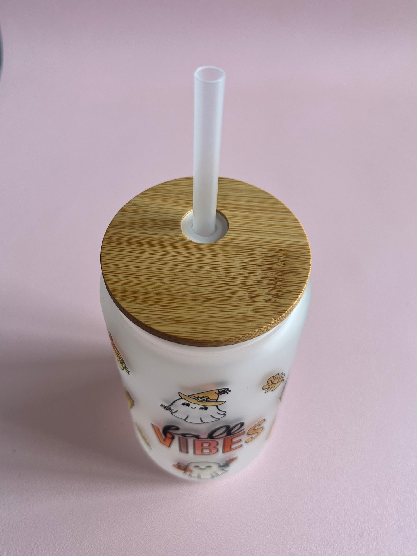 Tumbler with wooden lid and straw on a pink background