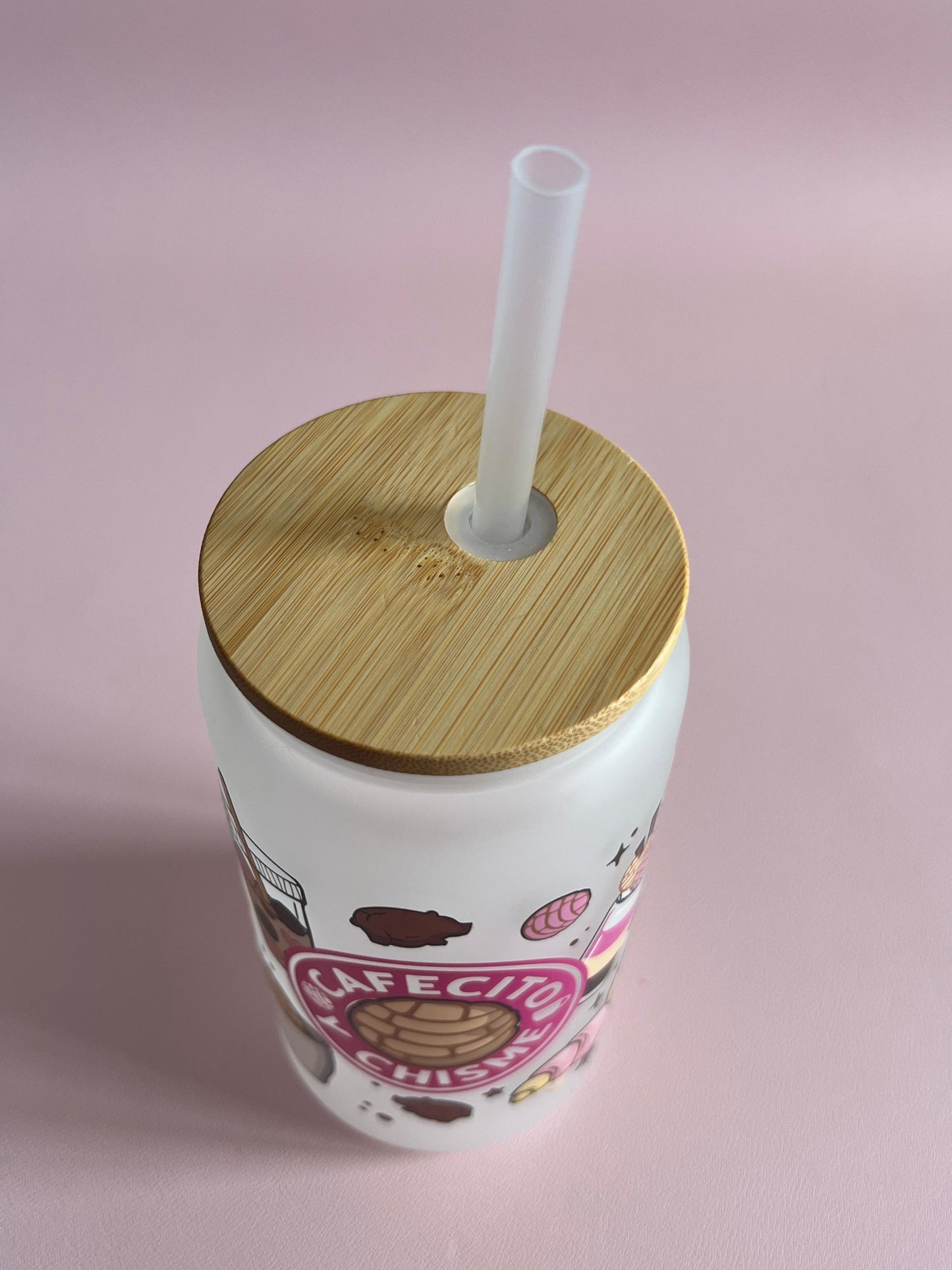 White tumbler with wooden lid and straw on a pink background