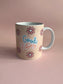 Beige mug with 'Good Vibes' text and flower designs on a pink background